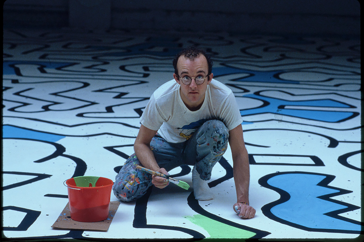 American artist and activist Keith Haring, painting the Palladium nightclub backdrop. Haring was openly gay and used his art to raise awareness of AIDS and fight for LGBTQ+ rights.